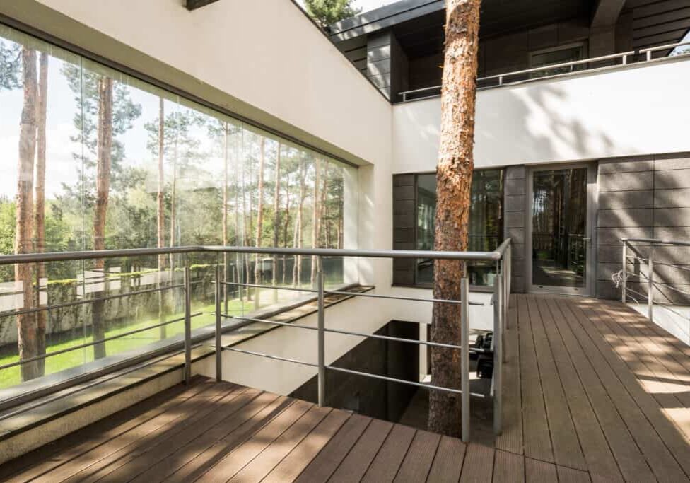 Big house in the forest with terrace and tree growing inside the house